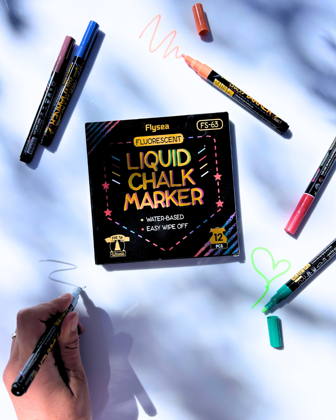 Box of Fluorescent Liquid Chalk Markers with markers and writings on a light blue background
