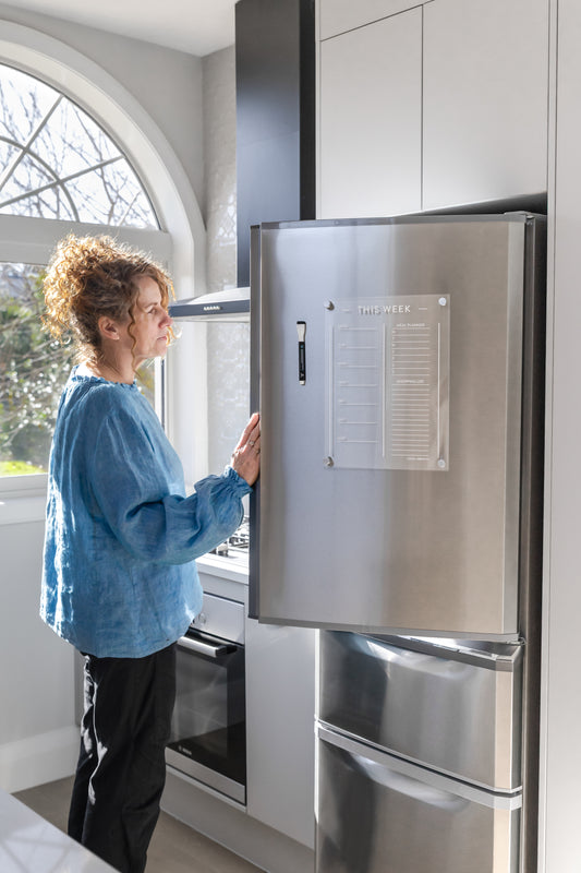 Person interacting with a stainless steel refrigerator in a modern kitchen.