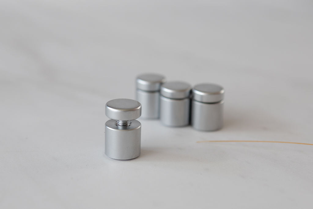 Set of silver metal magnets on a light gray background