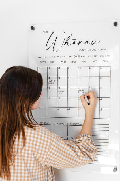 Close-up of woman using New Zealand-designed acrylic wall calendar, writing on frameless planner