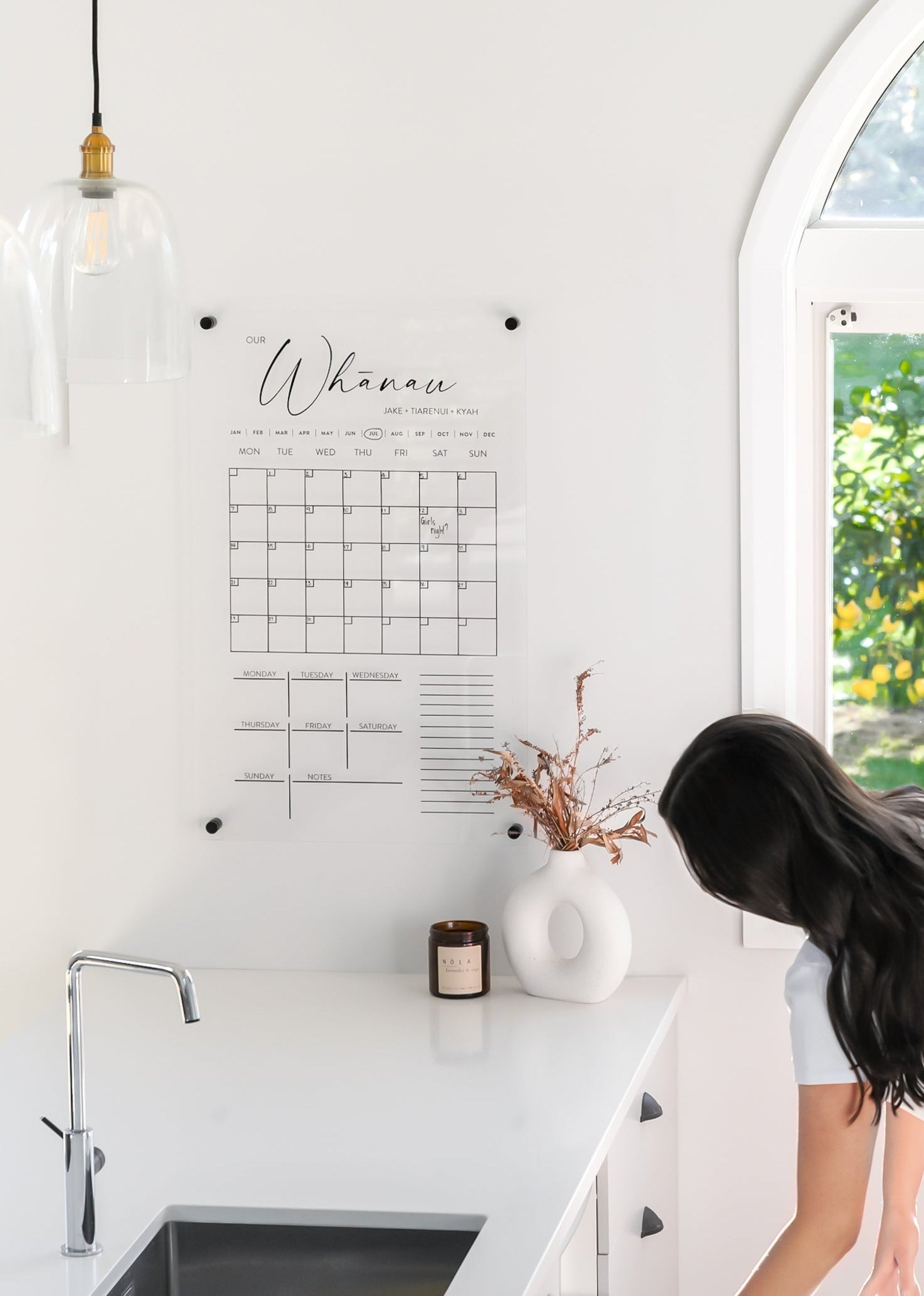 Acrylic wall calendar with frameless design, mounted using standoff brackets in a modern kitchen